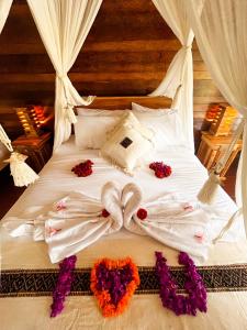 珀尼达岛Griyatama Bungalow的一张铺有白色床单和鲜花的床