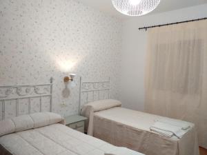 BedmarCortijo el Cercadillo的白色的客房设有两张床和窗户。