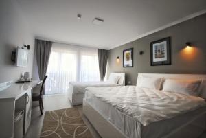 普里什蒂纳Hotel Callisto的卧室配有一张白色大床和一张书桌