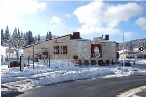 普雷芒翁La Serre - Centre du village - Départ des pistes de fond et Skibus à 50m的街道旁的大建筑,地面上积雪