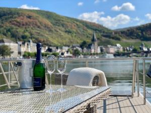 贝尔恩卡斯特尔-库斯KL Moselboote - Hausboot Niara的桌子上放着一瓶葡萄酒和两杯酒杯