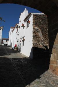 蒙萨拉什Casa Dom Dinis的一座白色的建筑,有石墙,有一个人坐在地上