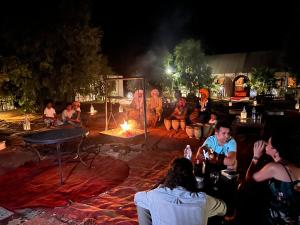 梅尔祖卡Luxury traditional Tent Camp的一群人晚上坐在火炉旁