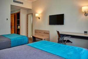 塔尔卡Hotel Diego de Almagro Talca Express的酒店客房设有两张床、一张桌子和一台电视。