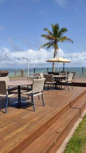 巴拉格兰德Barra Grande Pe na Areia Beira Mar的海滩上带桌椅的木制甲板