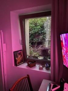 Suite privée avec accès jardin en coeur de village的粉红色的客房设有窗户、桌子和书桌