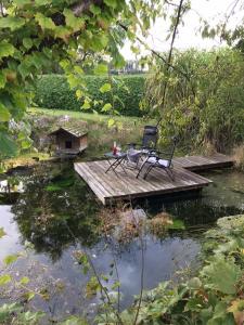 PeratschitzenKlopeinerperle的一张桌子和椅子,坐在池塘上的木桥上