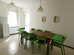 泰尔拉戈Villa Villi的一间带木桌和绿色椅子的用餐室