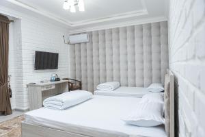 撒马尔罕AHMAD HOTEL的一间卧室设有两张床,墙上配有电视。