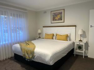 昆比恩Hamilton's Queanbeyan Motel的卧室配有一张带黄色枕头的大型白色床。