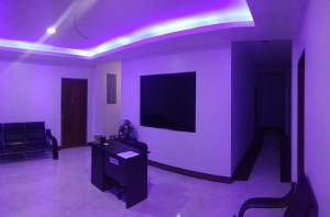 莫阿尔博阿Junie Pension House的客厅配有紫色照明和墙上的电视