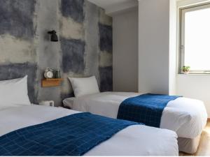 大阪HOTEL WAN OSAKA EBISU的一间卧室配有两张带蓝白色床单的床