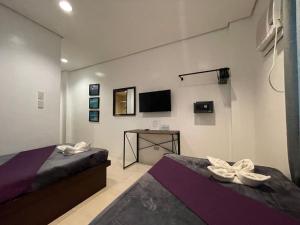 科隆Coron Ecolodge的一间卧室设有两张床,墙上配有电视。