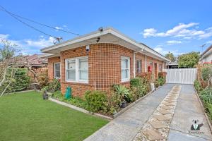 悉尼KozyGuru / Rockdale / Spacious Modern 2 Bedrooms Holiday Home NRO147的一座红砖房子,有草地庭院