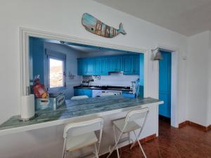 马德拉港Apartment on the sea的厨房配有蓝色橱柜和带椅子的柜台。