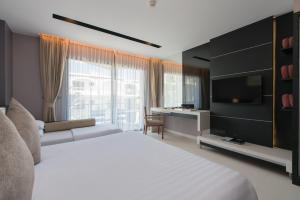 芭东海滩Patong Beachfront Studio 2 Mins Walk 2 Patong Beach的卧室配有一张白色大床和电视。