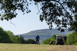 香槟谷古德森蒙克斯考尔高尔夫度假酒店的两个男子在田里用高尔夫球车行走