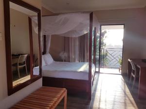 LimbeChinyonga Guesthouse的一间卧室配有一张带镜子的床和一个阳台