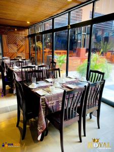 达累斯萨拉姆Royal Village Hotel的用餐室配有长桌子、椅子和窗户