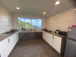 昆达桑Bayu Senja Lodge的一间厨房,配有白色的橱柜和大窗户