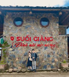 Văn ChấnKhông gian văn hóa trà Suối Giàng的一对夫妇站在石头建筑前