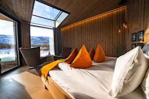阿尔塔Sorrisniva Arctic Wilderness Lodge的一间卧室配有一张带橙色枕头的大床