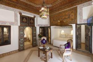 马拉喀什Riad Palais Des Princesses & Spa的一间卧室配有一张床、一张桌子和一个吊灯。