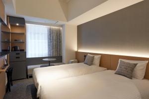 福冈CROSS Life Hakata Yanagibashi的酒店客房设有两张床和电视。