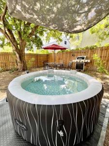 圣安东尼奥Belair Lux 3BR 3BA Home W Private Hot tub, 3k Arcade Games & private garage- 5mins to the Airport的后院的热水浴池,配有遮阳伞