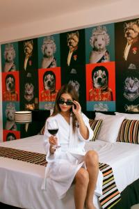 齐克拉约Mood Hotel Lifestyle的坐在床上的女人,喝一杯酒