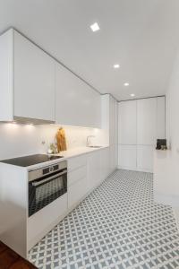 里斯本Casa Boma Lisboa - Design & Spacious Apartment With Balcony - Alvalade II的厨房配有白色橱柜和瓷砖地板。