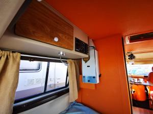 波尔蒂芒Rent a BlueClassics 's Campervan combi J9 en Algarve au Portugal的小房间,设有橙色的墙壁和窗户