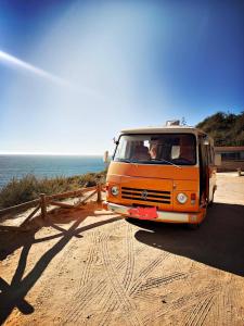 波尔蒂芒Rent a BlueClassics 's Campervan combi J9 en Algarve au Portugal的停在海边的土路上的橙色货车