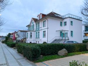 奥斯赛拜-屈隆斯博恩Ferienwohnung Windlicht的白色的房子,设有绿色的窗户和街道