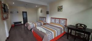 圣佩德罗拉拉古纳Hotel Porto Bello的客房设有两张床、一张桌子和一张书桌。