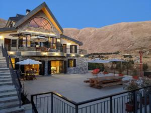 阿尔·阿尔兹Chalet de Charme, Cedars, Lebanon, Terrace Floor的大型房屋设有带桌子和遮阳伞的庭院