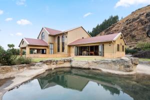 海姆维尔Drakensberg Luxury Accommodation - Misty Ridge的前面有池塘的房子