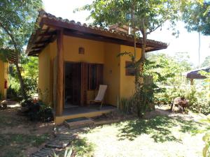 巴拉格兰德Pousada Ponta do Muta的前面有椅子的小黄色房子