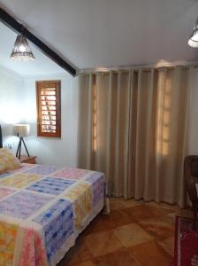 帕拉库鲁Pousada Yuste Beach Farm的一间卧室配有床和带窗帘的窗户