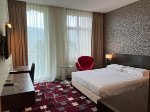 太平SSL商贸酒店的酒店客房,配有一张床和一张红色椅子