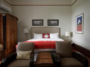 BloomfieldThe Eddie Hotel and Farm的一间卧室配有一张带红色毯子的床和两把椅子