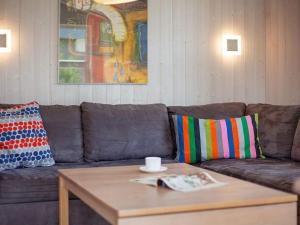 格洛米茨6 person holiday home in GROEMITZ的棕色的沙发,配有色彩缤纷的枕头和茶几