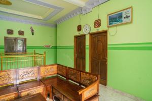 巴图RedDoorz Syariah near Batu Night Spectacular 3的一间设有绿色墙壁、木制家具和时钟的客房
