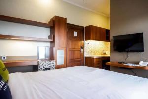 日惹Urbanview Rumah Kandjani Yogyakarta的卧室配有一张白色大床和一台平面电视。