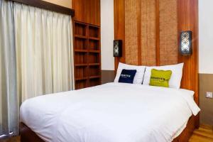 日惹Urbanview Rumah Kandjani Yogyakarta的卧室配有白色的床和3个枕头