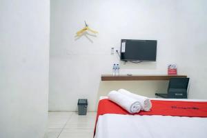 BelawanRedDoorz near Ekowisata Mangrove Belawan的卧室配有一张床,墙上配有电视。