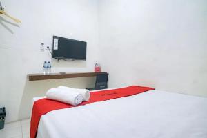 BelawanRedDoorz near Ekowisata Mangrove Belawan的一间卧室配有一张带红色毯子的床和一台电视。