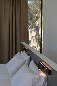 SívasO Mikros Kosmos Hotel Resort - Adults Only的窗户客房内的一张带白色枕头的床