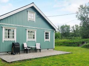 TranøyaHoliday home Tranøy的绿色房子,配有两把椅子和烤架