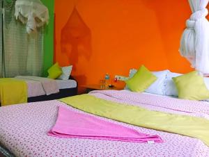 索拉哈Hotel Butterfly , Sauraha , Chitwan的一间卧室设有两张床和橙色的墙壁